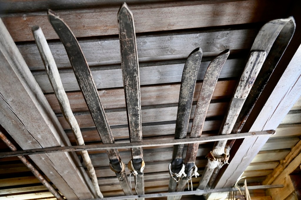 Hanging handmade wooden skis on a rustic wooden ceiling.