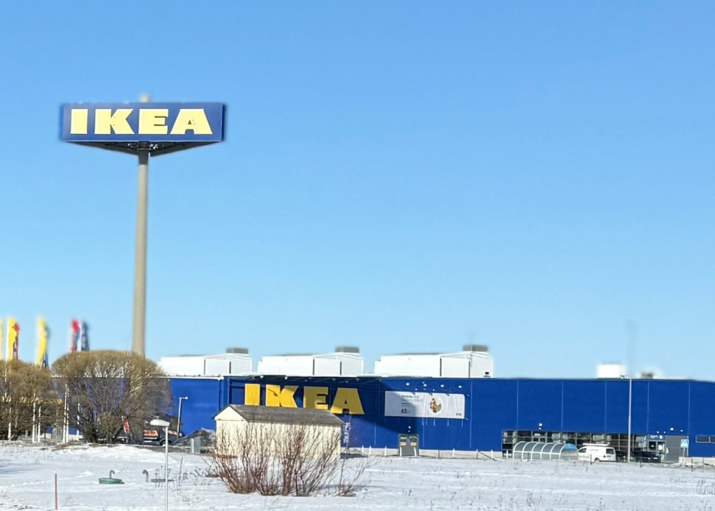 IKEA store with a large sign against a clear blue sky, surrounded by snow-covered ground.