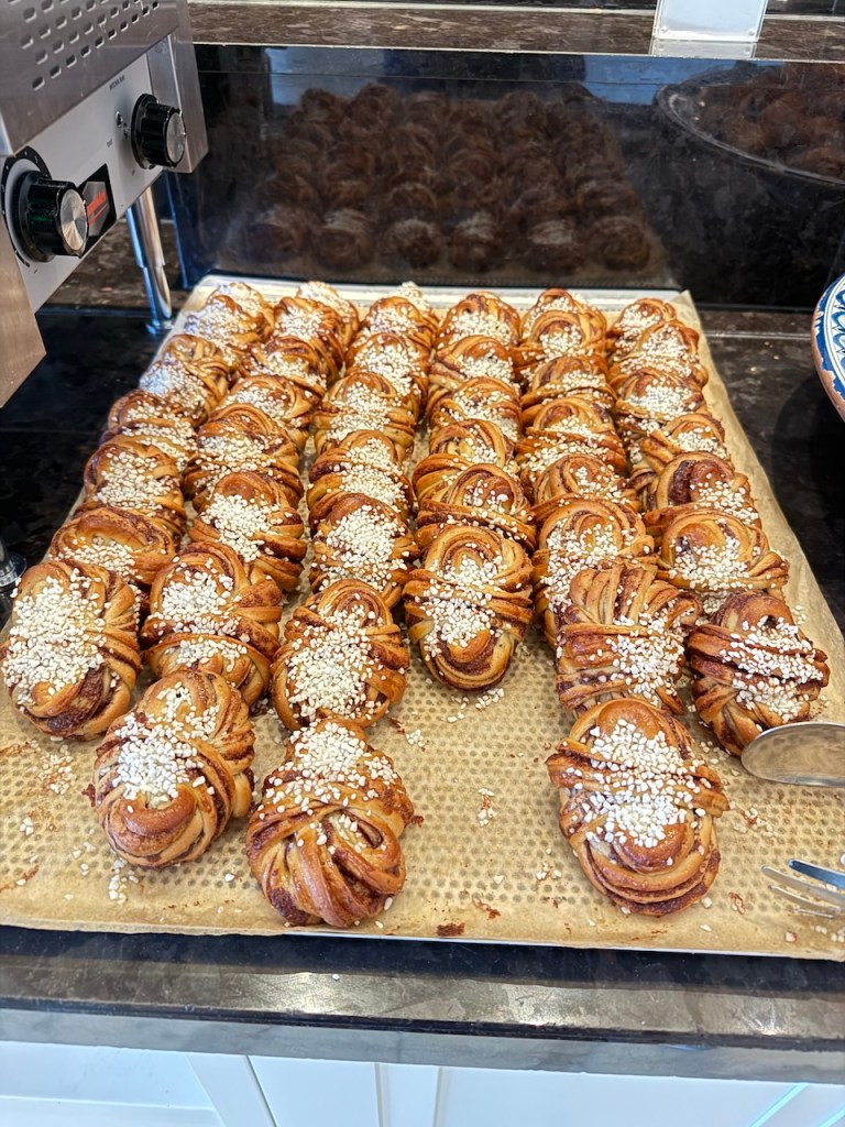 A tray filled with freshly baked cinnamon buns, also known as kanelbullar, topped with white sesame seeds.