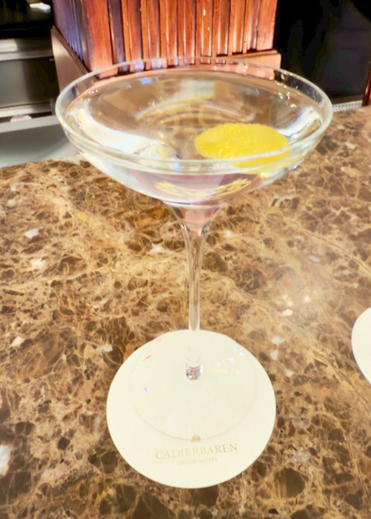 A martini cocktail with a lemon twist served in a stemmed glass on a circular coaster at the Cadier Bar, Grand Hotel.