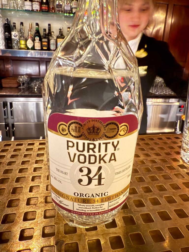 A bottle of Purity Vodka 34 showcased on a bar countertop with a bartender in the background.