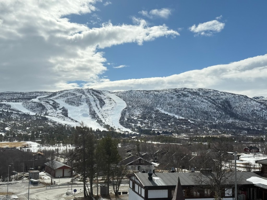 Snow-covered ski resort landscape with a clear blue sky and distant mountains in Norway.