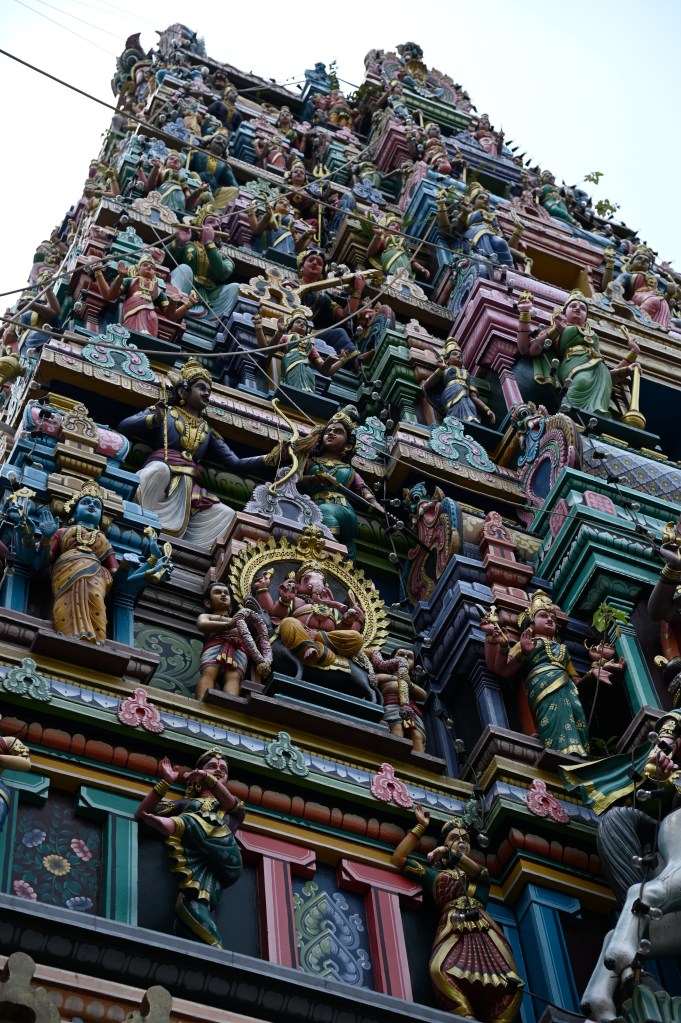 Close-up view of the ornate tower of the Hindu Sri Mahamariamman Temple, featuring colorful carvings of deities and decorative elements.