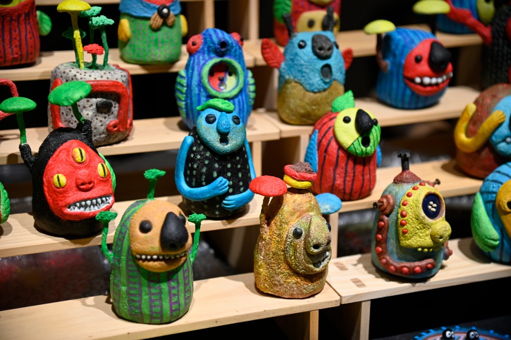 Colorful hand-crafted figurines resembling whimsical creatures, displayed on wooden shelves.