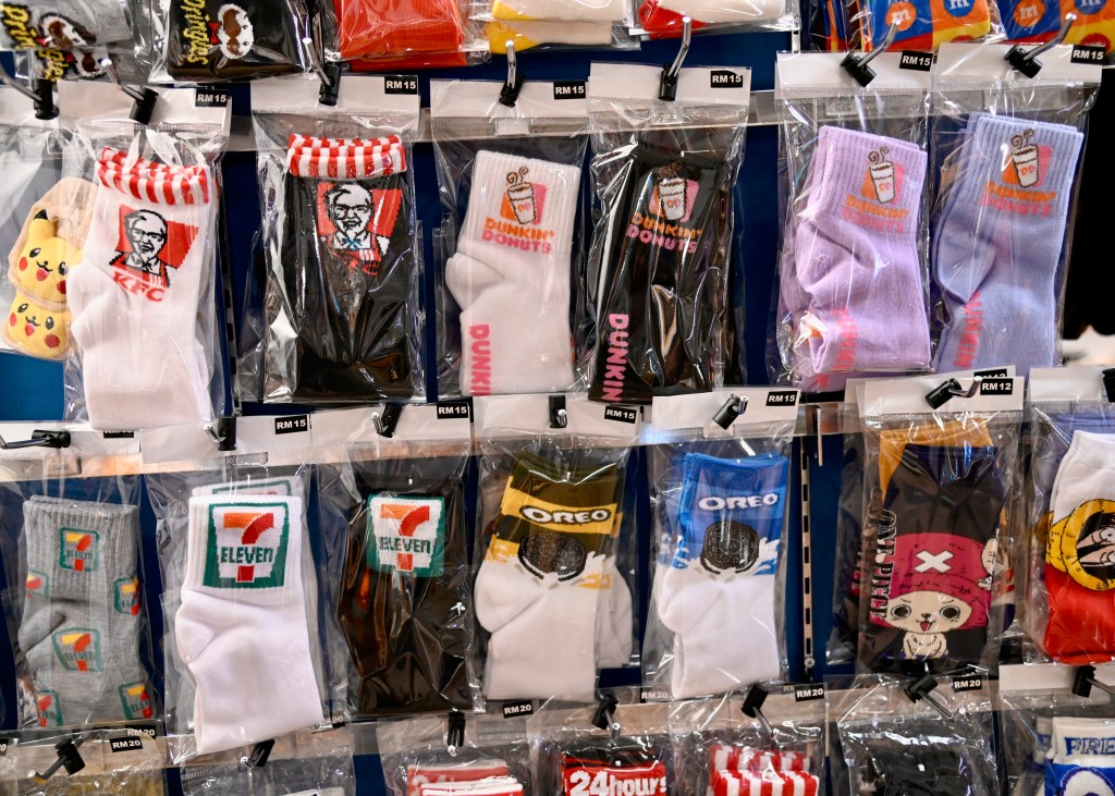 Display of various fun and branded socks in clear packaging, featuring designs from popular brands like KFC, Dunkin' Donuts, Oreo, and 7-Eleven.