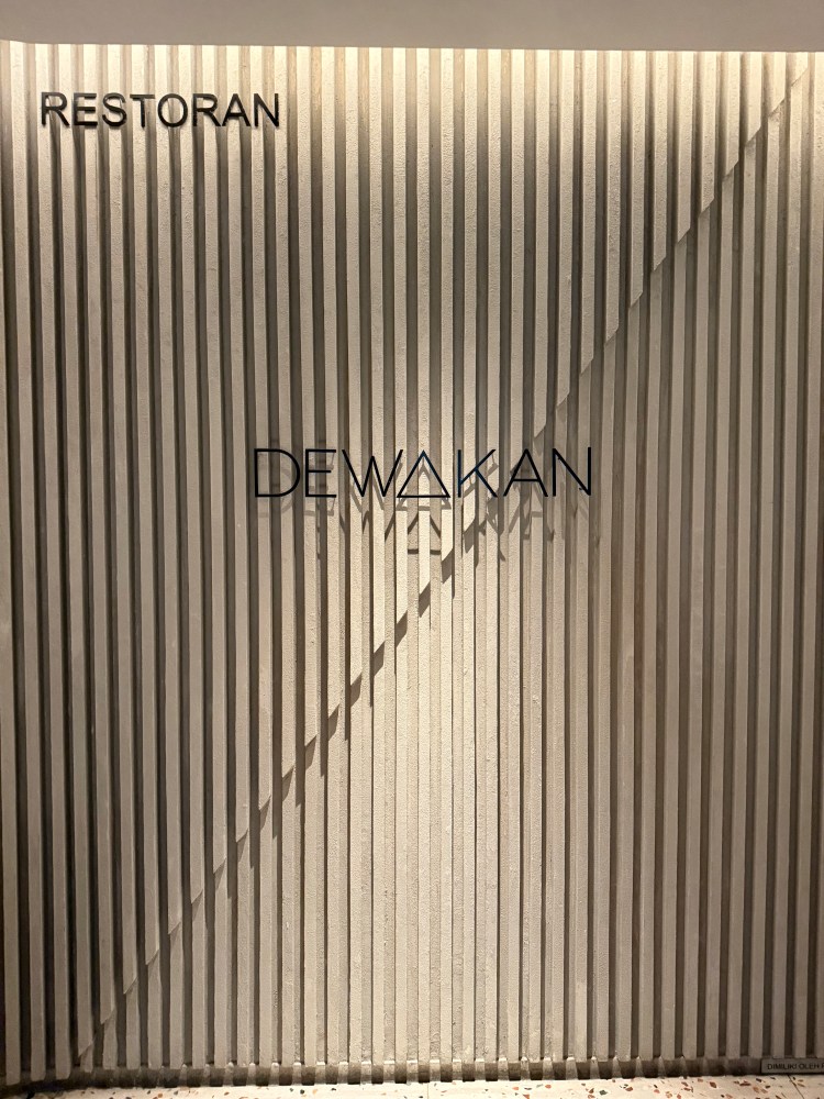 Stylish entrance wall of Dewakan restaurant featuring vertical lines and the name 'Dewakan' in an elegant font.